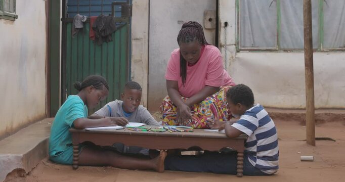 Poverty. Inequality.Black African woman home schooling her three young children at their shack in a township in Africa