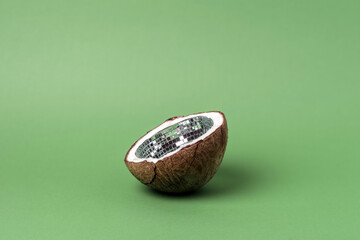 Open coconut shell with reflective disco mosaic interior on green background, surreal concept...