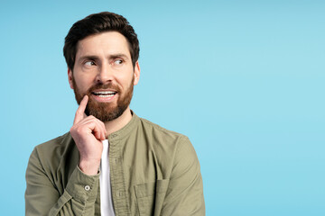 Happy Latin young man looking to copy space, holding hand near chin, isolated on pink