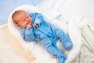 Baby boy crying  lying in nursery cocoon for newborns.,Baby is 1 month old. 