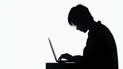 Silhouette of a person working intently on a laptop against a stark white background