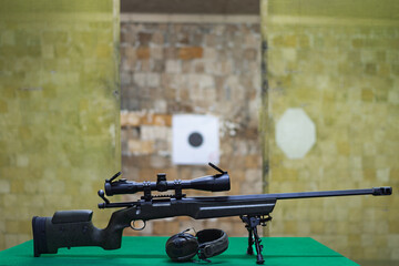American bolt action sniper rifle in a shooting range, with active headphones for shooting on the...