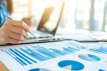 Female hand analyzing business graphs and charts on laptop in office setting
