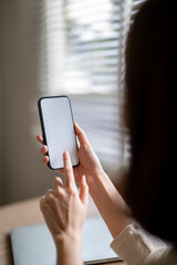 A woman is holding a cell phone and pointing at the screen