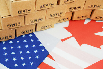 Tariffs between Canada and USA. Canadian and US flags with many carton boxes close up.	