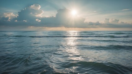 Obraz premium Serene seascape with gentle waves and bright sunlight streaming through clouds over tranquil ocean waters at dawn.