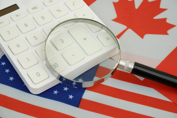 USA and Canadian flags with calculator and magnifying glass.	