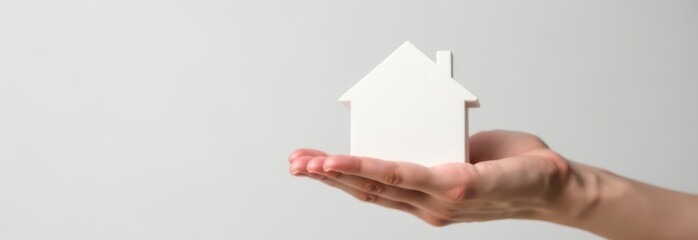 Obraz premium Real estate agent holding small house model in open palm with copy space.