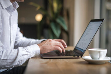 Man is sitting in an office and working on a laptop.
