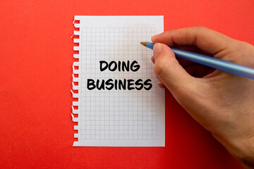 Doing business message written on white paper on red background. Conceptual doing business symbol. Copy space.