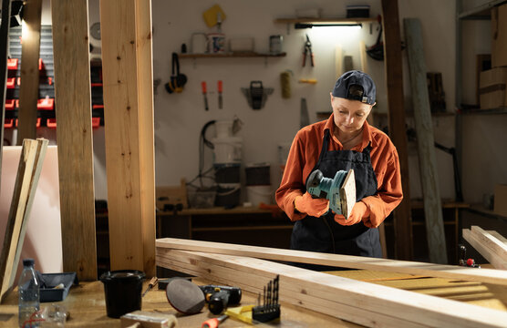 DIY maker and woodworking concept. Female carpenter holding sander machine standing in carpentry workshop - Powered by Adobe
