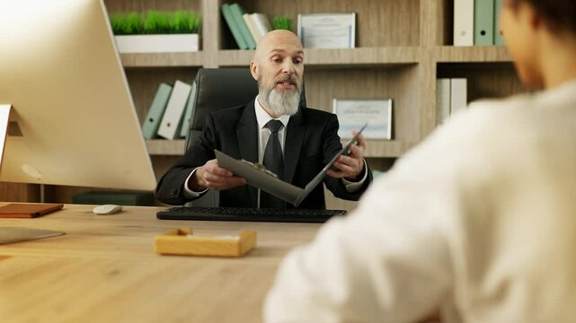 Senior job interviewer reviews a female candidate's CV, making a hiring decision