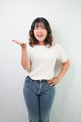 Beautiful young asian woman with wavy hair wearing white shirt is showing angry face expression and hand on waist gesture with sad face expression, isolated over white background.