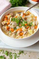 Delicious chicken noodle soup with vegetables on a deep plate with spoon fresh and homemade cooked
