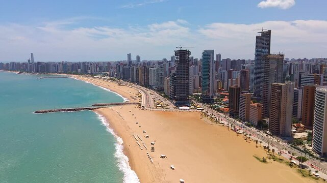 Stunning aerial view of Iracema Beach in Fortaleza, Ceara, Brazil. Golden sand, turquoise sea, and a modern skyline filled with skyscrapers. Busy avenue and vibrant waterfront