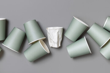 New light green paper cups and crumpled used white one on a grey top view, mockup