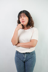 Beautiful young asian woman with wavy hair wearing white shirt is showing thinking or planning gesture, isolated over white background.