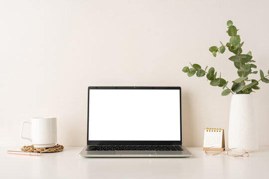 A clean and minimalistic workspace featuring a laptop, white coffee mug, and desk accessories