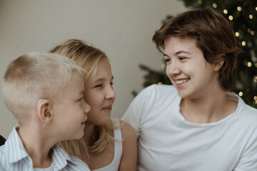 A loving mother with her son and daughter enjoys the magical atmosphere of Christmas and New Year. The family shares joyful moments, playing together, laughing, and creating warm holiday memories
