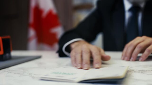 Canadian embassy officer stamps approved in a passport, confirming the entry