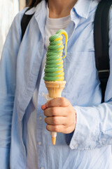 33 Flavors Day Young asian adult holding tall green spiral ice cream cone in hand