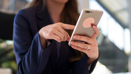 Close-up of a young Asian businesswoman using a smartphone while working in a bright and modern office