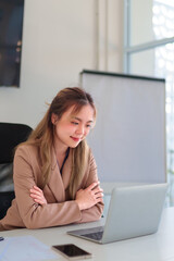 Young Asian businesswoman working on a laptop at her office desk in a clean and organized workspace