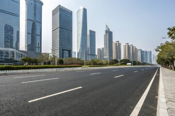 Wide asphalt road stretching through a modern cityscape with sleek skyscrapers and glass towers in the background, modern city, concrete highway