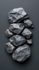 Fototapeta premium Natural dark stones arranged artistically on a sleek surface, showcasing textures and shapes in a minimalist style