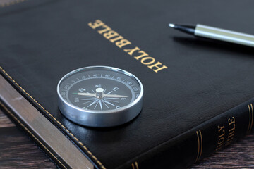 Compass and pen on holy bible book. Close-up. Selective focus. Biblical concept of Christian way,...
