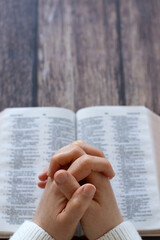Hands praying on top of open holy bible book. Copy space. Christian gratitude, praise, and prayer...