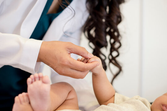 Close up of baby holding doctors hand