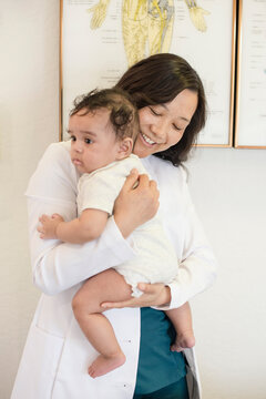 Doctor holding baby and evaluating back