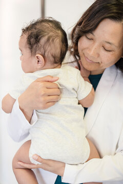 Close up of doctor holding baby and looking at back