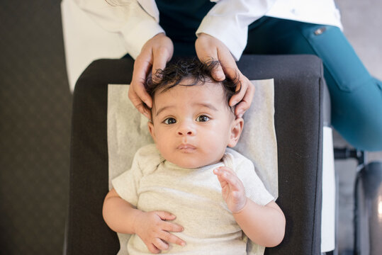 Doctor checking baby's head in office