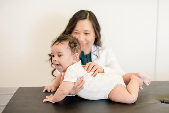 Baby smiling while laying doing tummy time with doctor