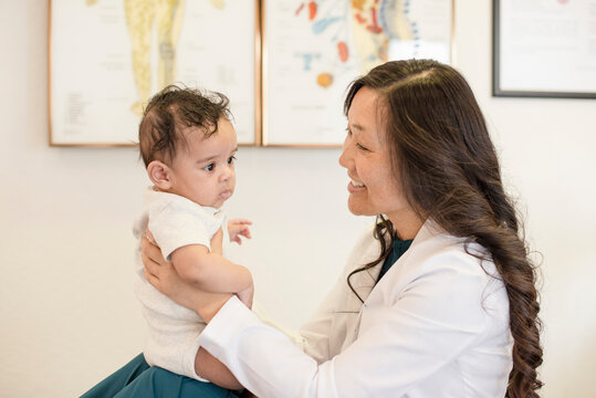 Baby sitting on doctors knees smiling