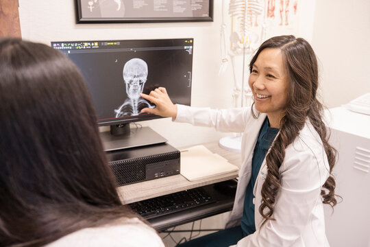 Doctor showing patient x-ray of skull on computer
