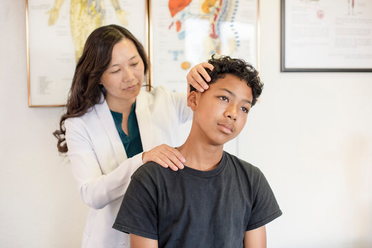 Woman doctor adjusting young patients neck