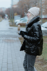 A beautiful young woman walks through a snowy city on a winter day, joyfully chatting on her phone. She smiles and laughs, radiating warmth and happiness. The clip captures a cozy lifestyle vibe