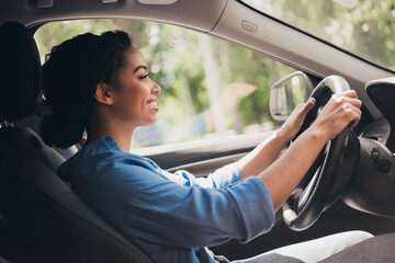 Young woman enjoying driving a car in an urban setting on a sunny day
