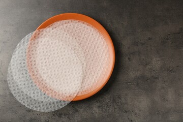 Edible rice paper sheets on grey textured table, top view. Space for text