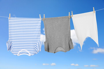 Different clothes drying on washing line against blue sky