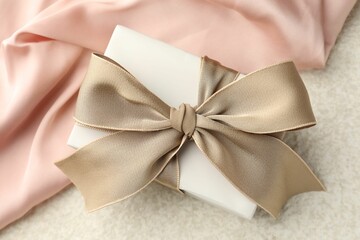 Gift box with beautiful bow and cloth on light background, top view