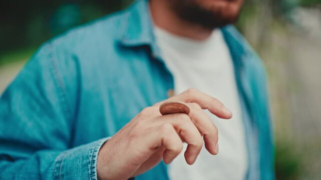Close-up of man twisting coin in his hand. Closeup of hand moving coin between fingers - sleight of hand, in background urban cityscape