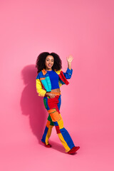 Cheerful young woman posing with vibrant style against a pink background, exuding fashion and liveliness