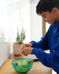 teenage boys and household chores. preteen boy helping around the house making a healthy salad.