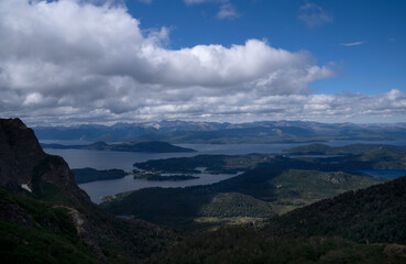 Naklejka premium Patagonian landscape. View of the hills, Nahuel Huapi lake, and forest under a magical sky with clouds, seen from the top of Cerro Lopez in Bariloche