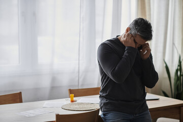 Fototapeta premium Handsome man in a cozy room engaged in a deep phone conversation while reflecting