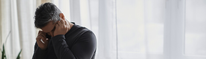 Handsome man distressed while talking on the phone in a softly lit room